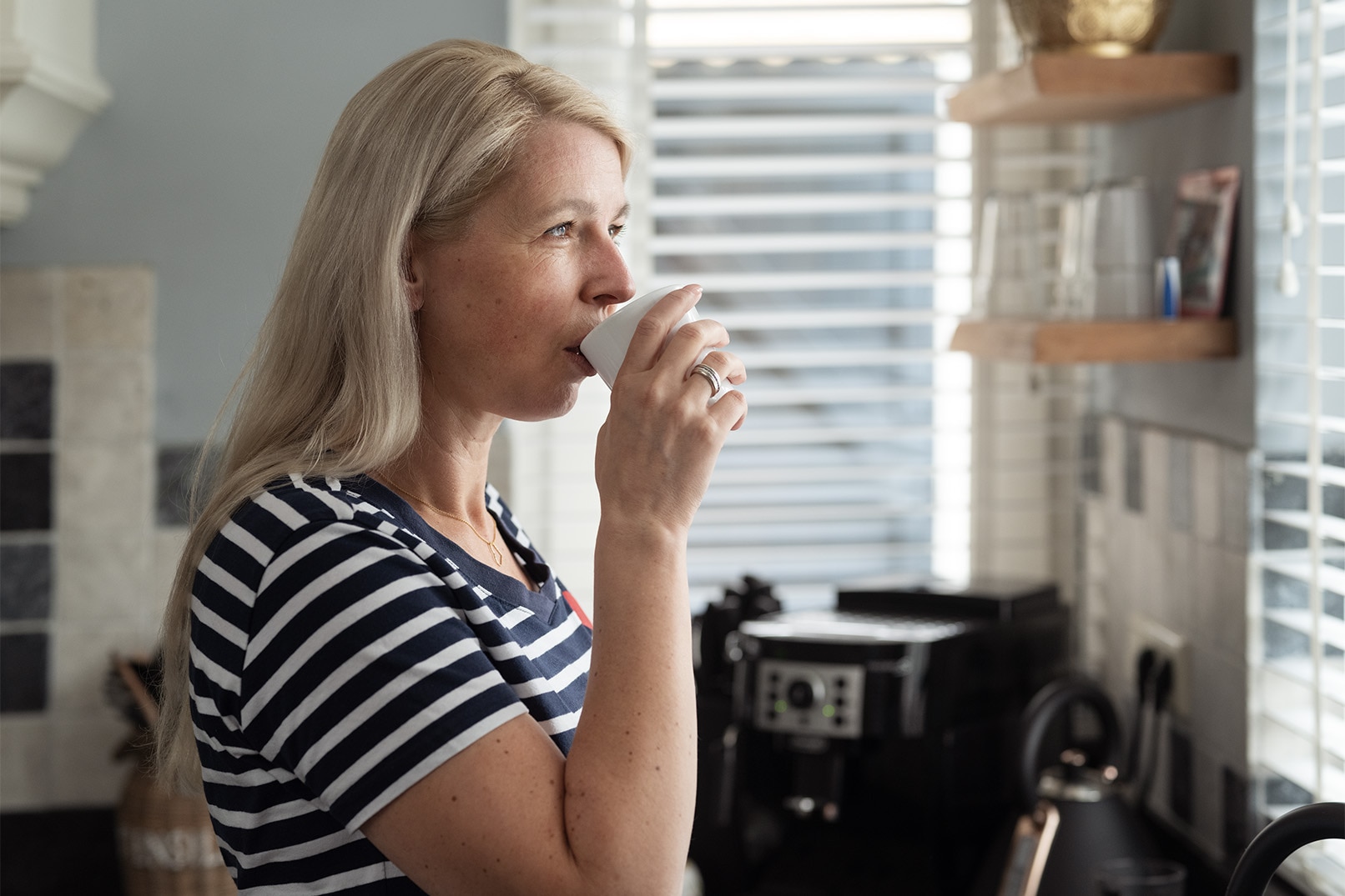 Tankefull kvinne drikker av en kaffekopp
