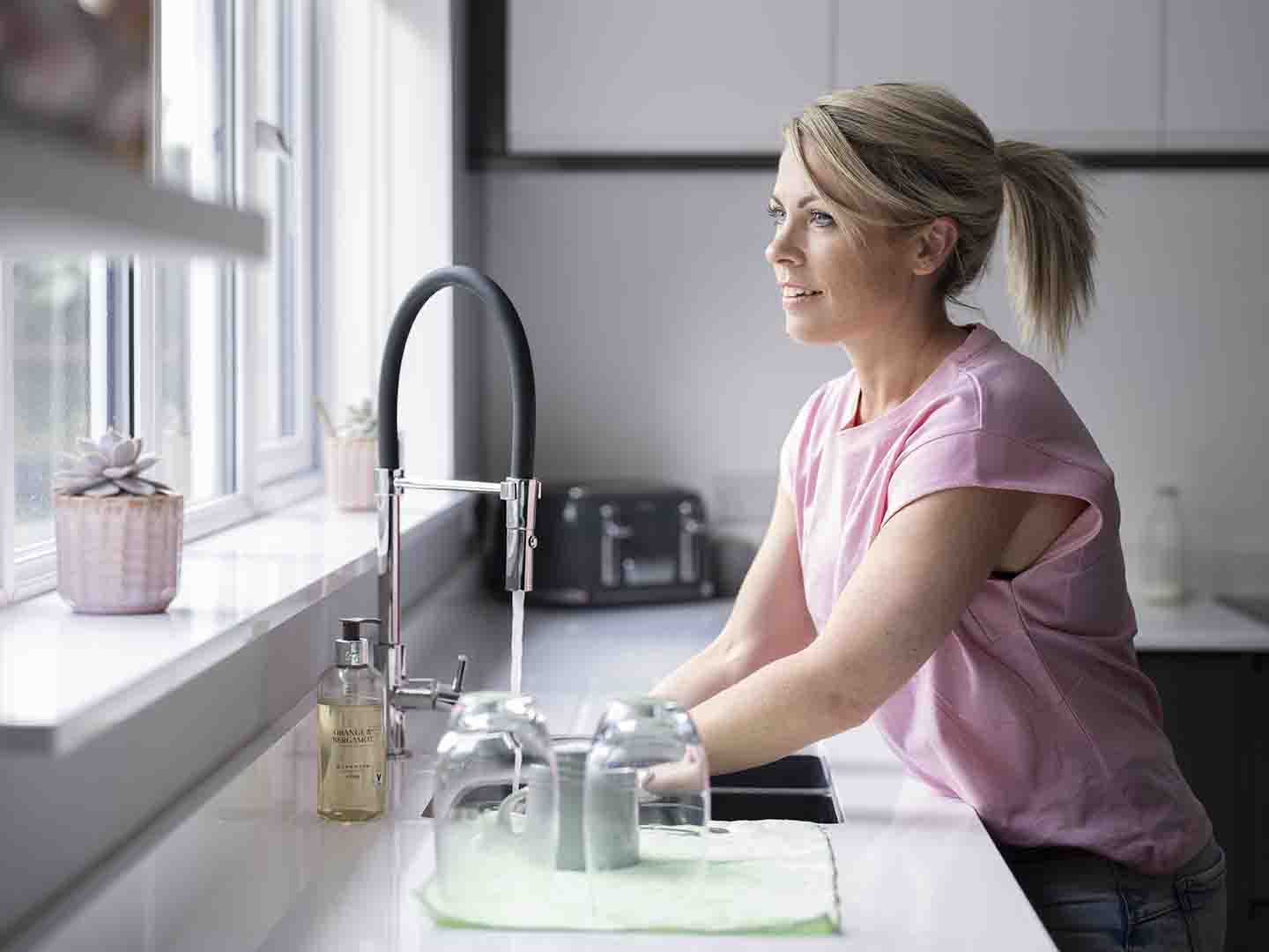Kvinne vasker hender på kjøkken