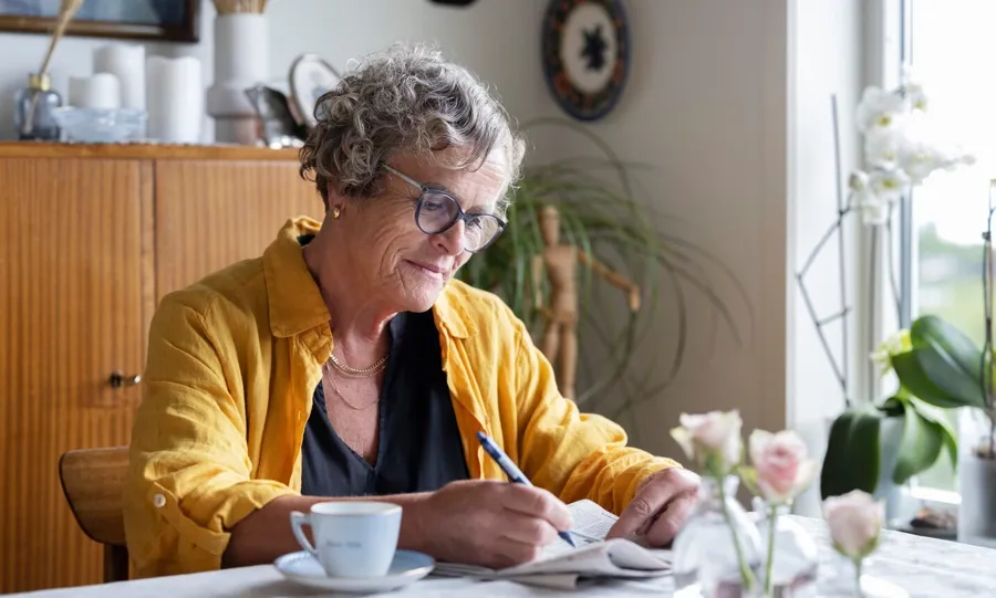 Bilde av Gullborg sittende ved bordet sitt med kaffe og avis. Blæreproblemer er ikke uvanlig når man lever med MS. Faktisk 4 av 5 personer som lever med MS rammet av kontinensproblemer på et eller annet tidspunkt i livet. 