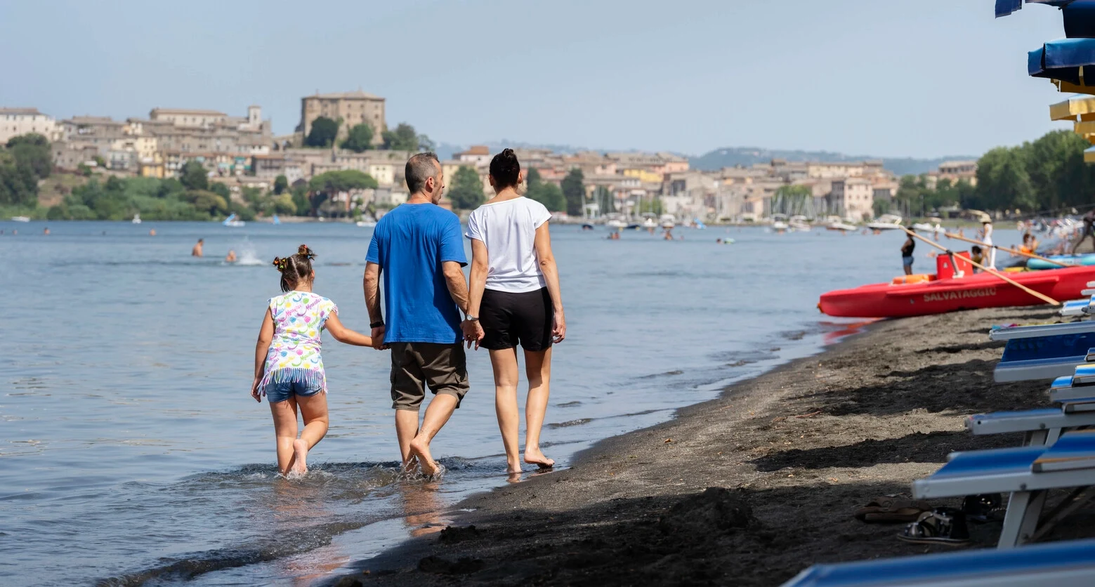 Foto av Andrea som går langs stranden med familien. Andrea lever med MS og bruker TAI for å håndtere tarmproblemene sine. 