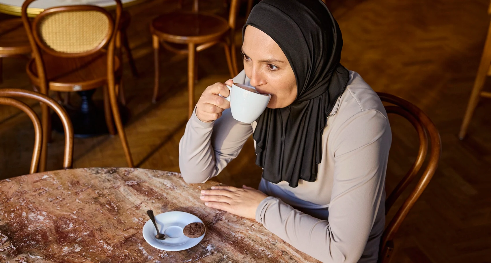 Portrettfoto av Fikria sittende på en kafé. Fikria lever med MS, og tarmproblemer er en del av livet hennes. Hun bruker Peristeen Light for å håndtere symptomene sine.