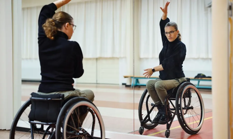 Foto av Marianne i dansestudioet sitt. Marianne har oppdaget rullestoldans, og hun danser rumba, paso doble og chachacha sammen med dansepartneren sin. 