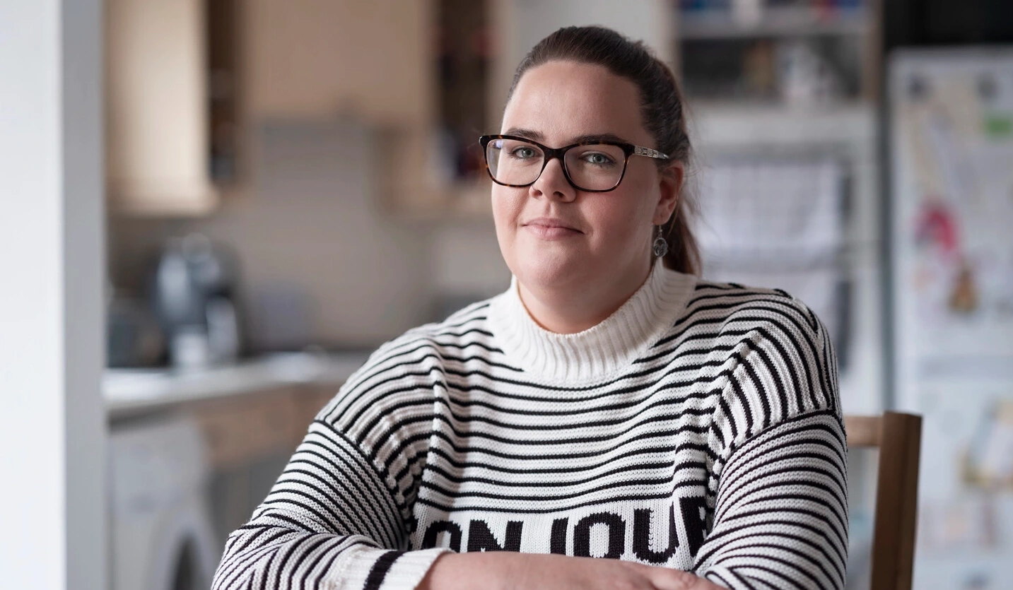 Sarah, som bruker intermitterende kateter og lever med MS, sitter ved et bord. 