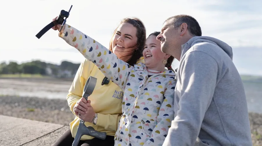 Foto av Sarah og familien som tar en selfie sammen på stranden. Det tok Sarah lang tid å koble blæreproblemene sine til MS-diagnosen.  