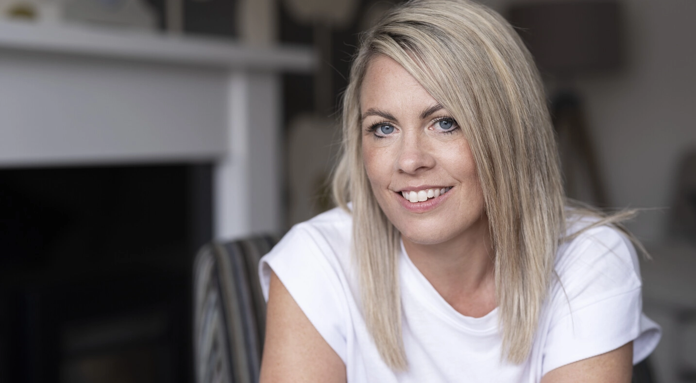 Laura, som bruker SpeediCath® Compact Eve og Peristeen® Plus, sitter i stuen sin. 