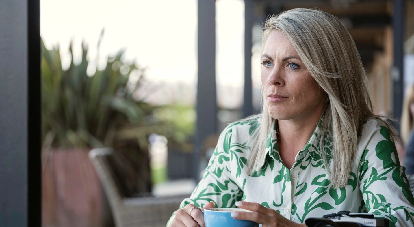Foto av Laura sittende ved et bord med en kopp kaffe. Denne artikkelen gir støtte og praktiske forslag som kan hjelpe deg med kateterisering og irrigasjon. 